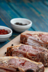 Raw pork meat and ingredients on a board on blue desk