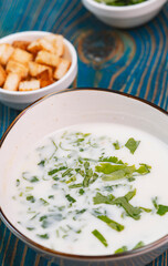 yogurt soup with herbs and crackers on a blue wooden table