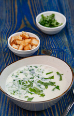 yogurt soup with herbs and crackers on a blue wooden table