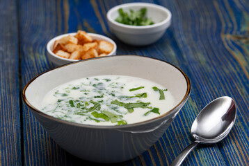 yogurt soup with herbs and crackers on a blue wooden table