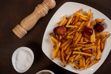 Potatoes with sausages, cut into slices and fried in oil, in rustic style. Fried potatoes with sausage on a plate