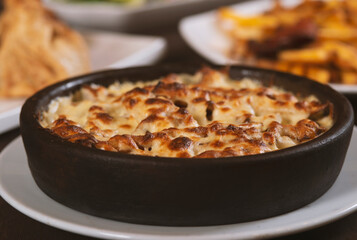 Mushroom and meat casserole covered with melted cheese and served in a dark dish on the table