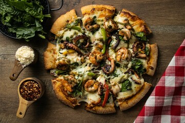 Top view of a pizza surrounded by ingredients on a rustic background