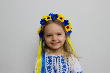 Little ukrainian blond girl on white background,smiling toddler in national ukrainian costume vyshyvanka and flower crown.