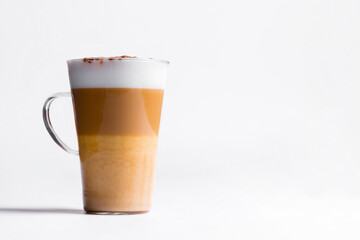 Latte macchiato in a tall glass on a white background. Cafe latte layered with milk in a high drinking glass. Minimalism. Сopy space
