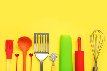 culinary background, culinary accessories on a yellow background - slotted spoon, dough knife, spatula, whisk, brush, skewers, silicone mat, rolling pin, ladle with copy space, culinary background