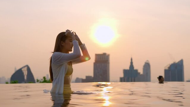 smiling laugh happiness summer vacation moment asian woman yellow bikini hand hold sun glasses while enjoy weekend leisure summer moment laugh smile cheerful on rooftop swimming pool sunset