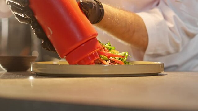 Close-up view portrait of beautiful delicious salad being decorated with herbs and sauce by professional successful chef working at kitchen of fancy restaurant. Cooking concept.