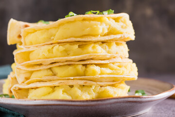 Close-up of Stacks of Kystyby - thin tortillas filled with mashed potatoes and onions on a plate.