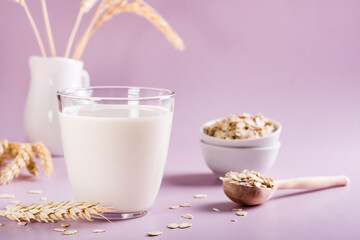 Homemade oat milk in a glass and oatmeal on the table. Alternative to lactose