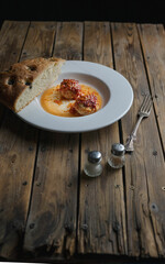 meatballs and a piece of focaccia on a white plate and a wooden table