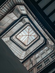 Low angle shot of a square building with glass ceiling and a lot of windows from inside