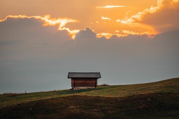Small wooden hut surrounded by the beautiful Dolomites mountains during the sunset