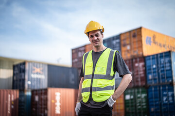 Caucasian warehouse worker in uniform with hard hat standing in container port terminal. Area logistics import export and shipping.