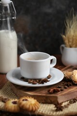 cup of coffee on a piece of wood with some cookies, milk and some spike behind