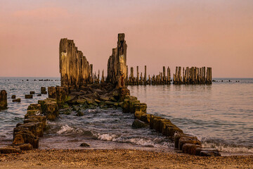 Old ruined wooden pier and a sandy beach