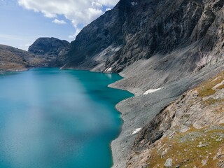 Aerial view of rocky mountains surrounded by lake in Usseglio