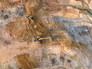 Excavator on earthmoving at construction site, aerial view.