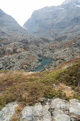 Scenic shot of a small lake surrounded by rocks in the Alps on a foggy day