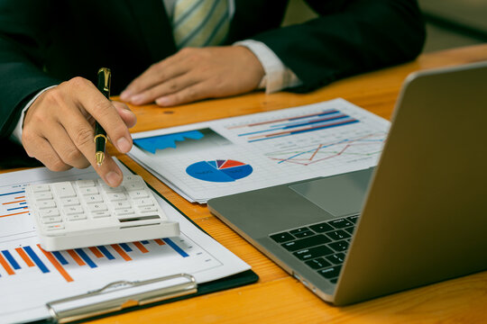 Accountant pressing calculator to make monthly financial report or company profit at desk and calculate income, taxes and expenses. Invoice. Credit card for employee payroll.