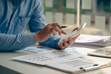 Accountant pressing calculator to make monthly financial report or company profit at desk and...