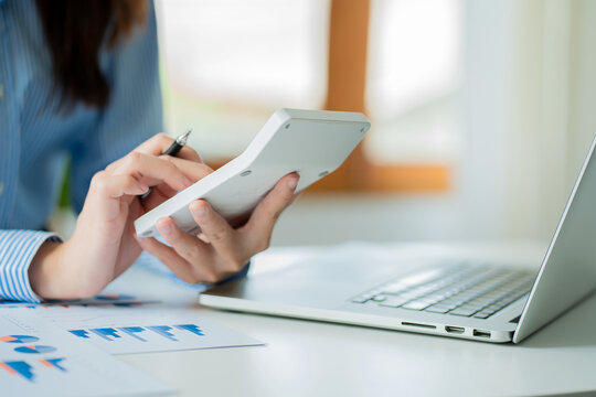 Accountant pressing calculator to make monthly financial report or company profit at desk and calculate income, taxes and expenses. Invoice. Credit card for employee payroll.