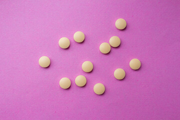 Yellow pills isolated on a pink background. Top view, flat lay.