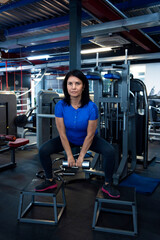 A woman doing physical exercise with dumbbell in the gym. Lower body workout. Sport and fitness.