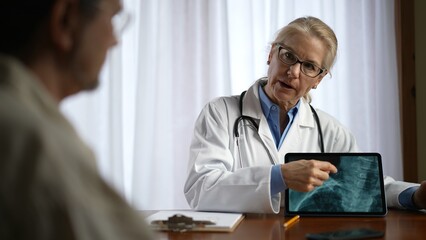 Doctor is shows X-ray images to patient on tablet pc computer. Concept of doctor discuss personal...