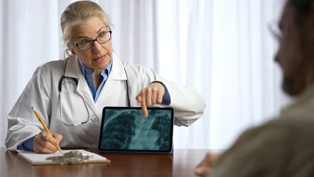 Doctor is shows X-ray images to patient on tablet pc computer. Concept of doctor discuss personal healthcare.