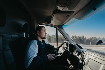 male truck driver with a smartphone in his hands is driving, shipping.