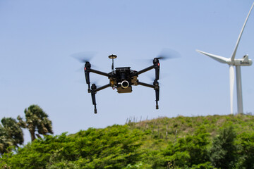 DJI drone hoovering next to windmills