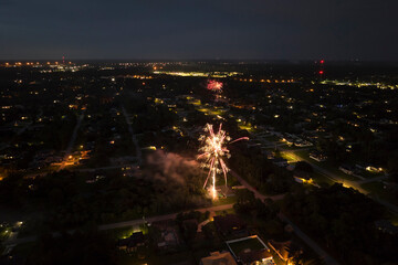 Aerial view of bright fireworks exploding with colorful lights over suburban houses in residential...