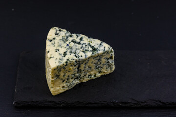 Piece of the blue cheese with mold on slate board