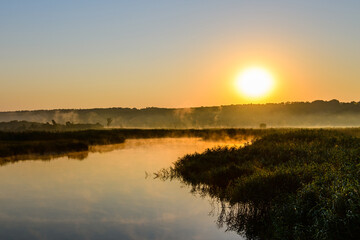 Naklejka na ściany i meble Fog above the water surface. Sunrise at river