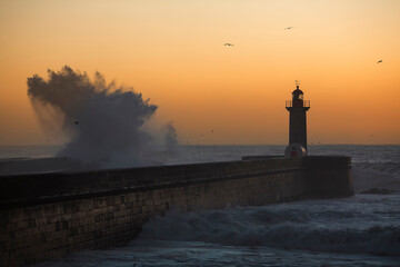 Fototapeta na wymiar Big wave at the lighthouse against the background of the sunset. Atlantic, Portugal.