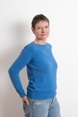 Paris, France - 03 18 2023: Studio shot of a mature woman with short hair posing and wearing a blue sweater with cufflinks