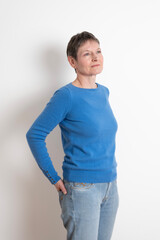 Paris, France - 03 18 2023: Studio shot of a mature woman with short hair posing and wearing a blue sweater with cufflinks