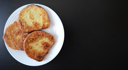 photo a white plate with croutons on a dark wooden background, a breakfast dish, fried bread