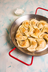 dumplings with potatoes and sour cream in a frying pan