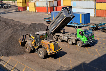 Operations with coal in  seaport. Loading coal on bulk carrier. Coal loading by cranes on bulk carrier
