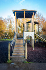 Fototapeta na wymiar Children's playground wooden play structure fort with wood step ladder bridge and high tower.