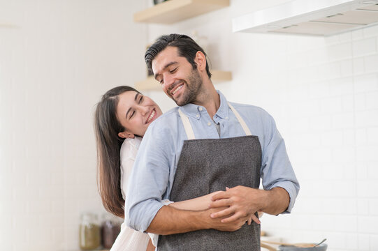 Happy couple in love cooking in the kitchen at home and hugging