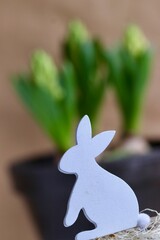 Wielkanoc. Wiosenny króliczek z drewna na tle zielonych kwiatów. Wielkanocne dekoracje i...