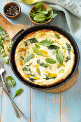 Healthy frittata or stuffed omelette in pan on rustic wooden background. Italian omelette with organic spinach and bell pepper. Copy space.