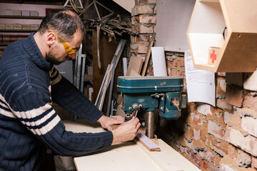 A carpenter works in a furniture workshop with various tools and a board