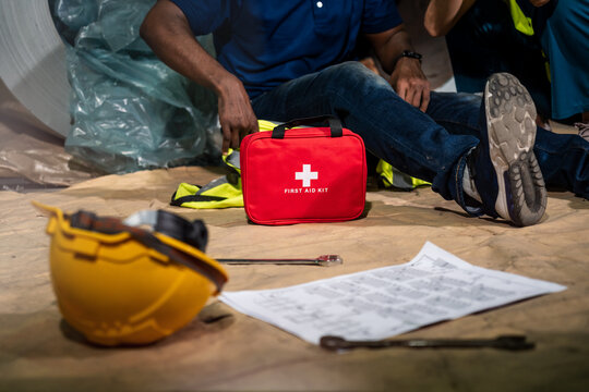 Emergency staff in safety suit use first aid kit to help a man who has an accident in factory workplace, First aid training in industrial company.