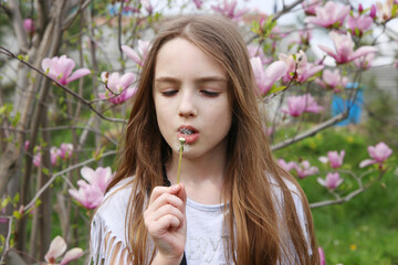 little girl blowing on a dandelion