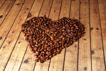 Heart shape made from coffee beans on wooden surface.