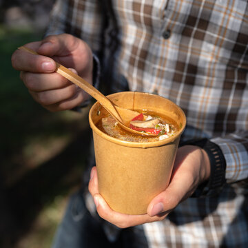 Takeaway food, soup in takeaway paper cup close-up in hands